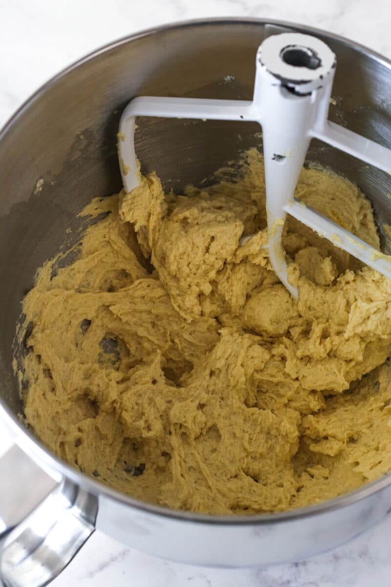 Mixing eggs and vanilla into creamed butter and sugar to make cookie dough.