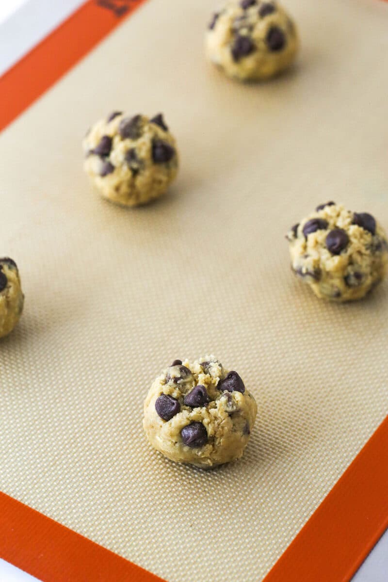 Balls of oatmeal chocolate chip cookie dough on a baking sheet ready to be baked.