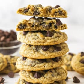 A stack of oatmeal chocolate chip cookies. The top cookie is broken in half.