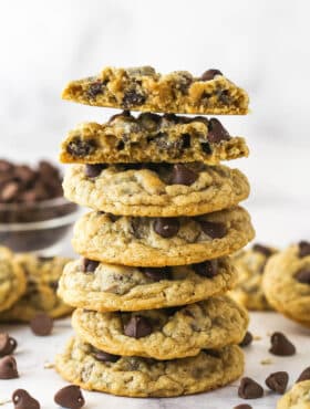 A stack of oatmeal chocolate chip cookies. The top cookie is broken in half.