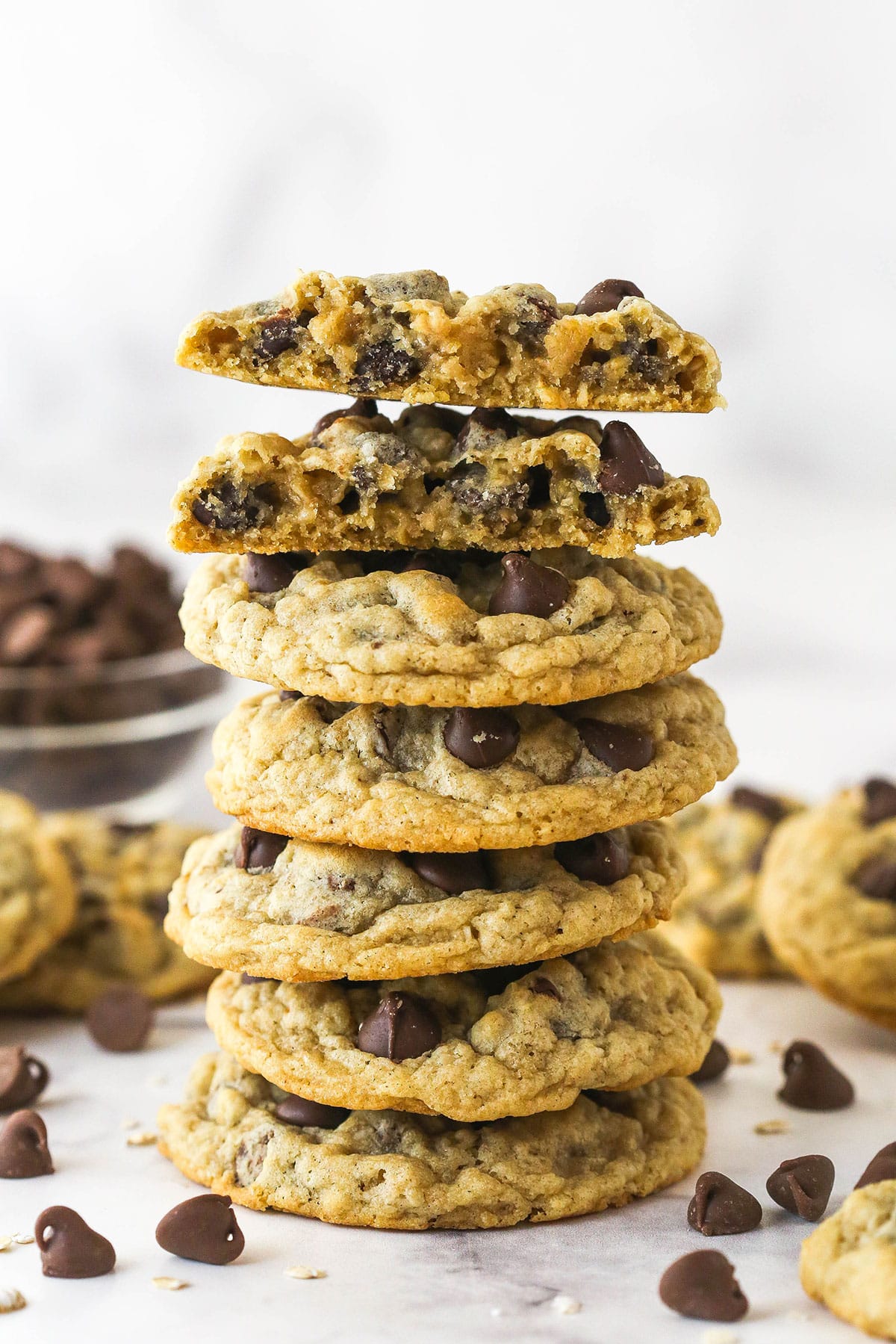 A stack of oatmeal chocolate chip cookies. The top cookie is broken in half.