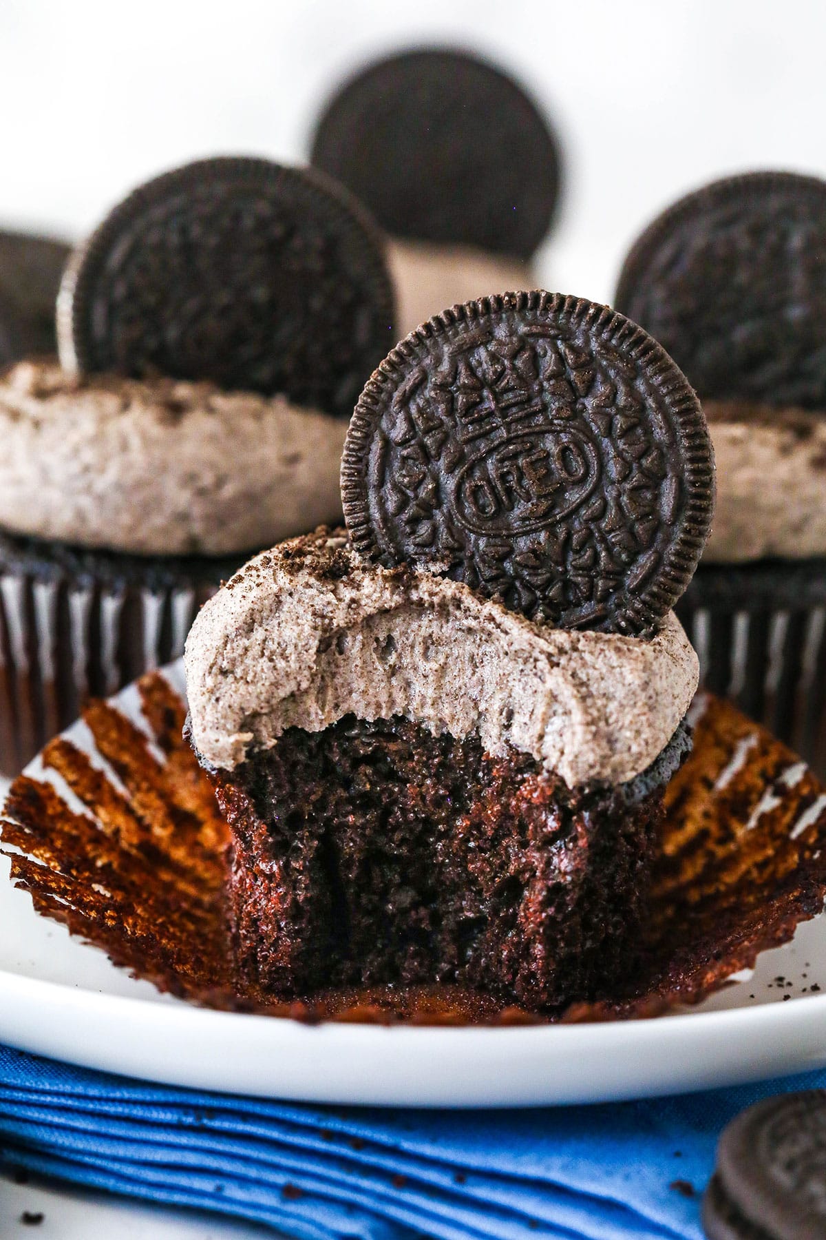 These Oreo Cupcakes are the answer to your Oreo craving! Creamy, Oreo-packed vanilla buttercream sits atop super moist chocolate cupcakes. An Oreo cupcake with a bite taken out of it.