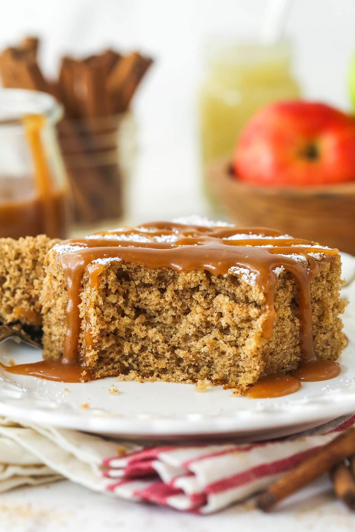 A slice of applesauce cake with caramel sauce drizzled over it and a bite taken from it.
