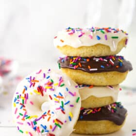 A stack of baked donuts with one donuts leaning against it.
