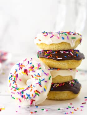 A stack of baked donuts with one donuts leaning against it.