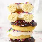 A stack of baked donuts. The top one is cut in half.
