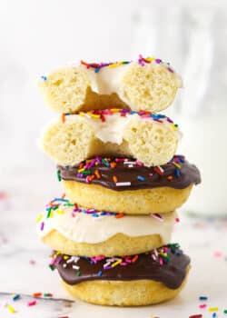 A stack of baked donuts. The top one is cut in half.