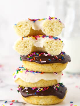 A stack of baked donuts. The top one is cut in half.