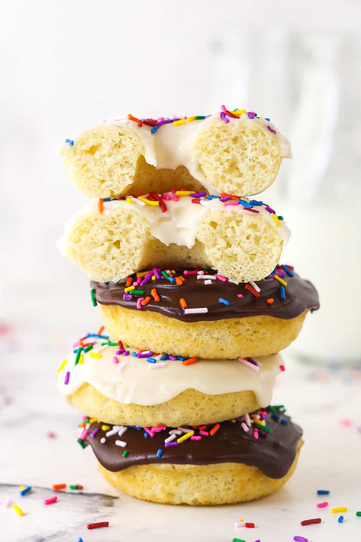 A stack of baked donuts. The top one is cut in half.