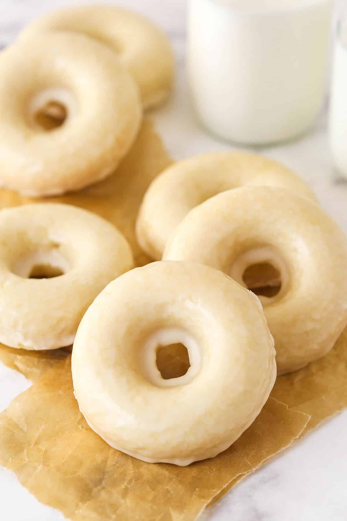Glazed baked donuts on parchment paper squares.
