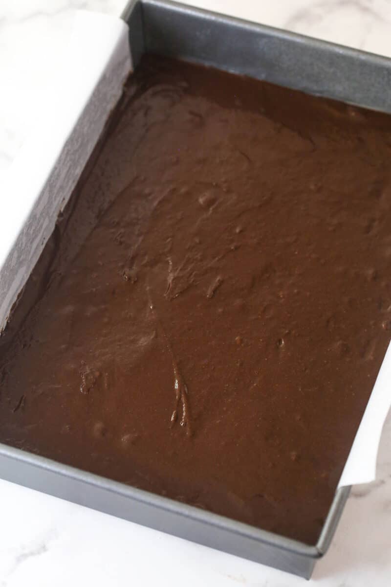 Spreading brownie batter in the bottom of a baking pan.