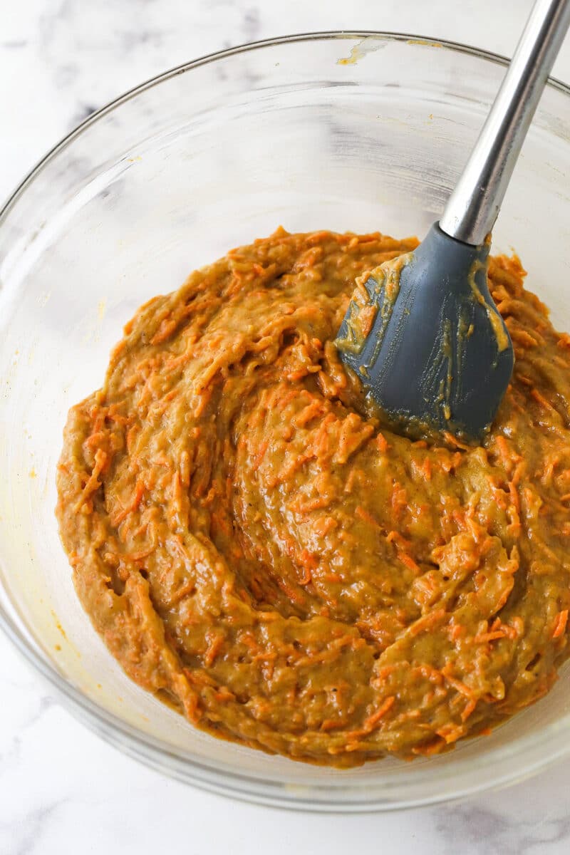 Folding grated carrots into carrot cake batter.