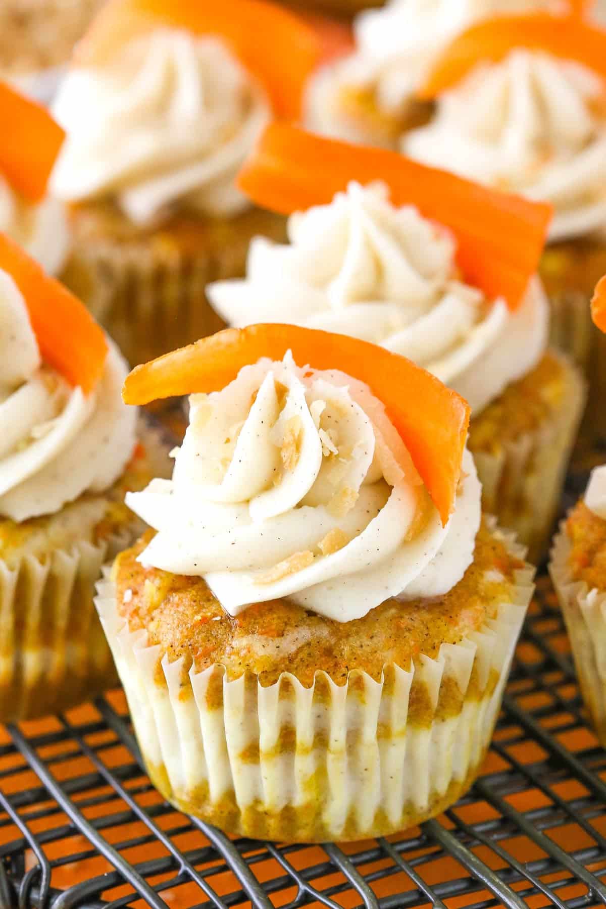 Close up of a carrot cake cheesecake swirl cupcake with more cupcakes in the background.