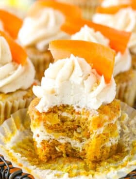 An unwrapped carrot cake cheesecake swirl cupcake with a bite taken out of it.