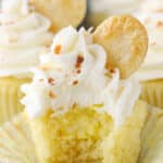 An unwrapped coconut cream pie cupcake with a bite taken out of it to show filling.
