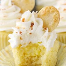 An unwrapped coconut cream pie cupcake with a bite taken out of it to show filling.