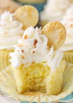 An unwrapped coconut cream pie cupcake with a bite taken out of it to show filling.