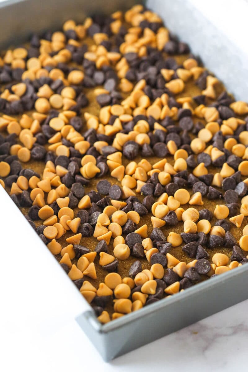 Scattering chocolate chips and butterscotch chips over graham cracker crust.