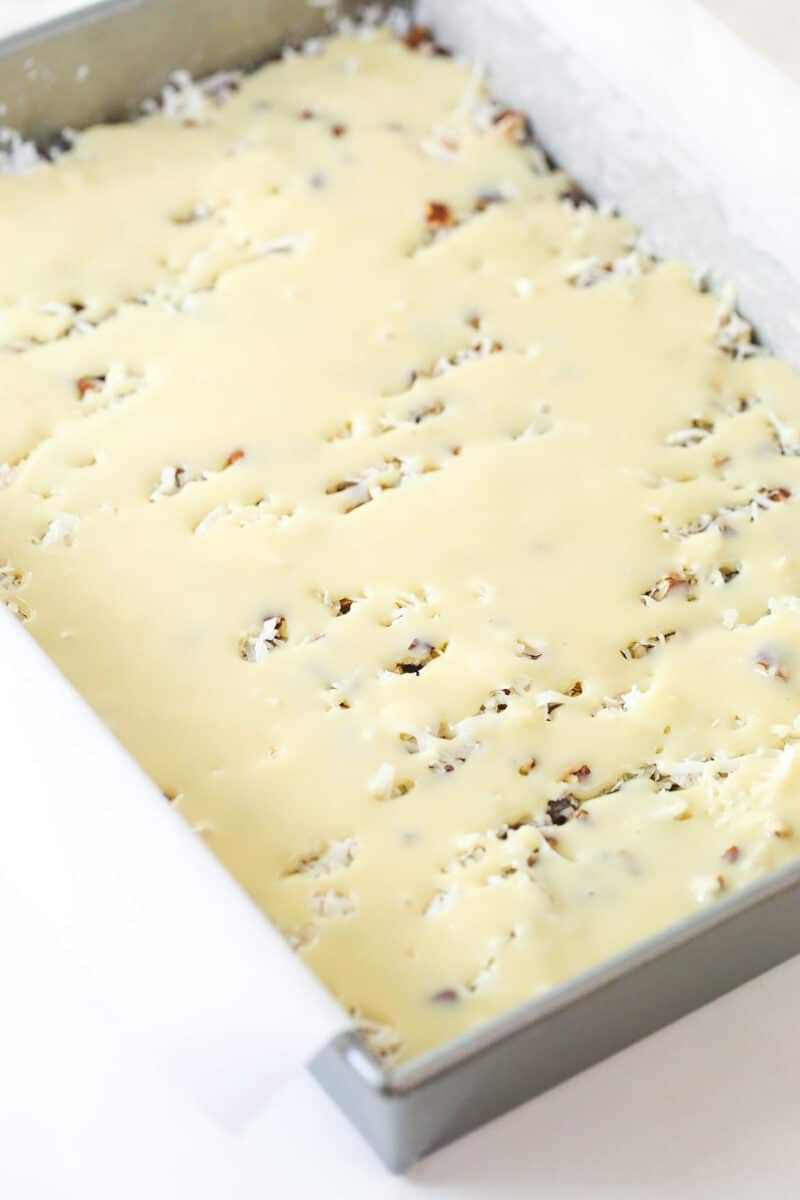 Drizzling sweetened condensed milk over magic cookie bars before baking.