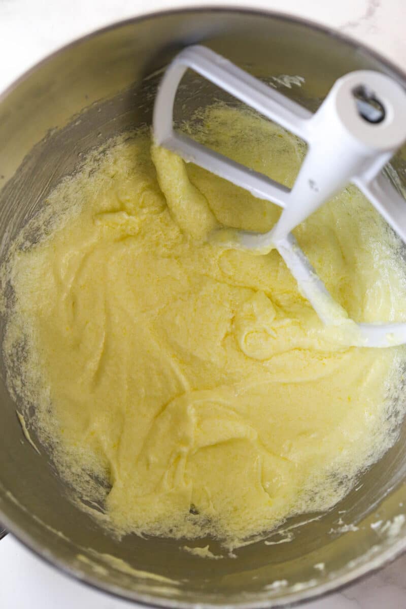Mixing eggs into creamed butter, oil, and sugar.
