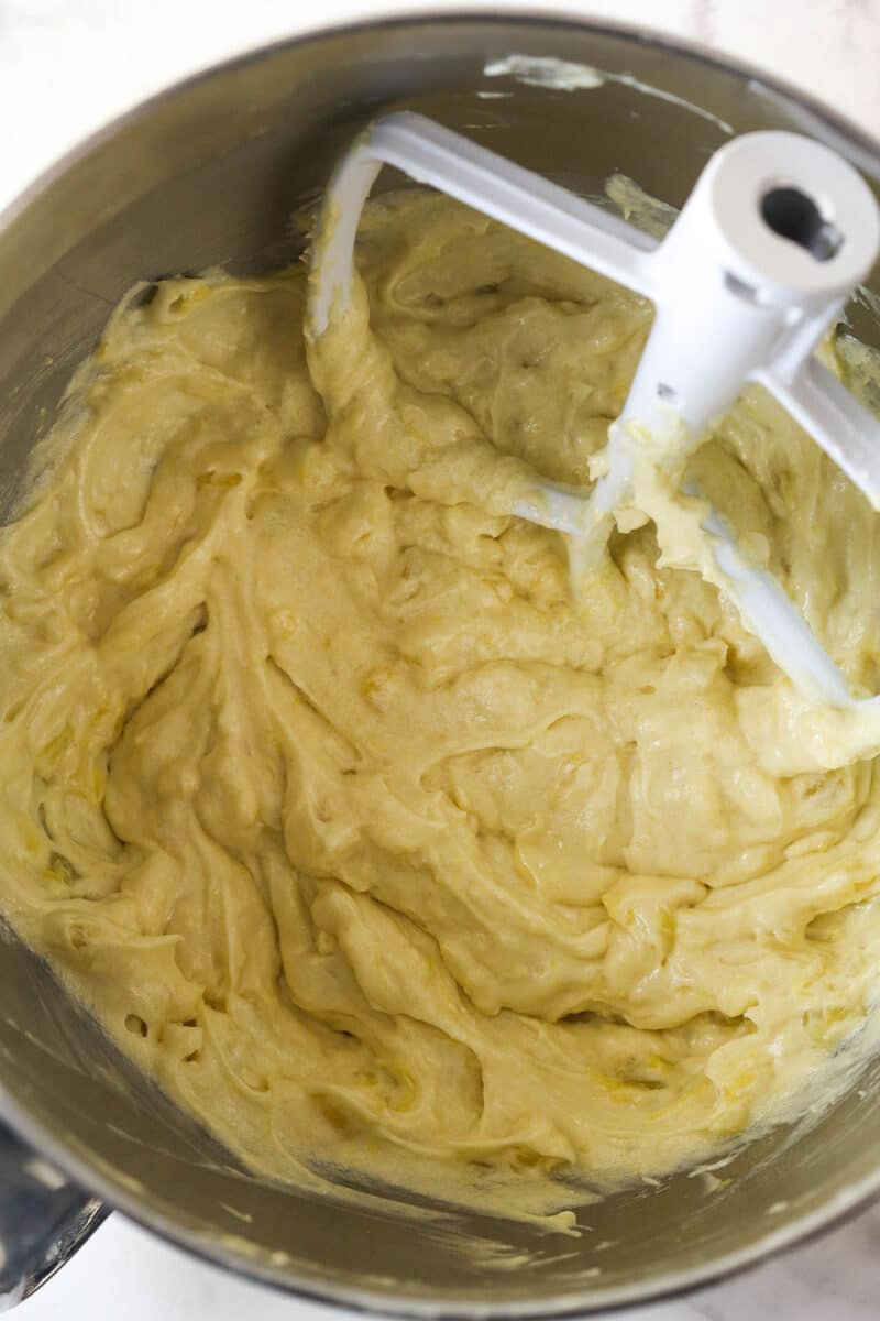 Alternating mixing canned pineapple and dry ingredients into pina colada cupcake batter.