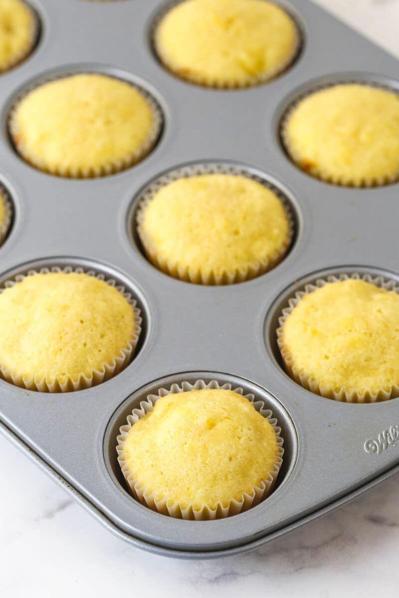 Pineapple cupcakes cooling in a pan.