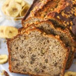Slices of banana nut bread leaning against a banana nut loaf.