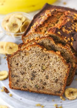 Slices of banana nut bread leaning against a banana nut loaf.