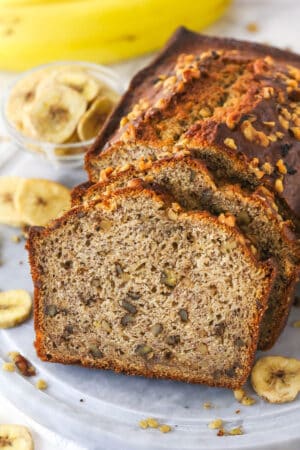 Slices of banana nut bread leaning against a banana nut loaf.