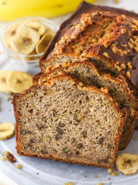 Slices of banana nut bread leaning against a banana nut loaf.