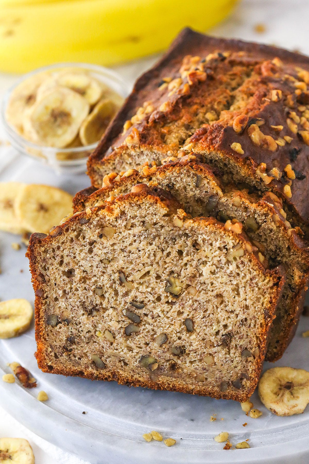 This easy Banana Nut Bread is top-notch. Supremely moist with BIG banana flavor and a hint of cinnamon, it's sure to become your new go-to! Slices of banana nut bread leaning against a banana nut loaf.