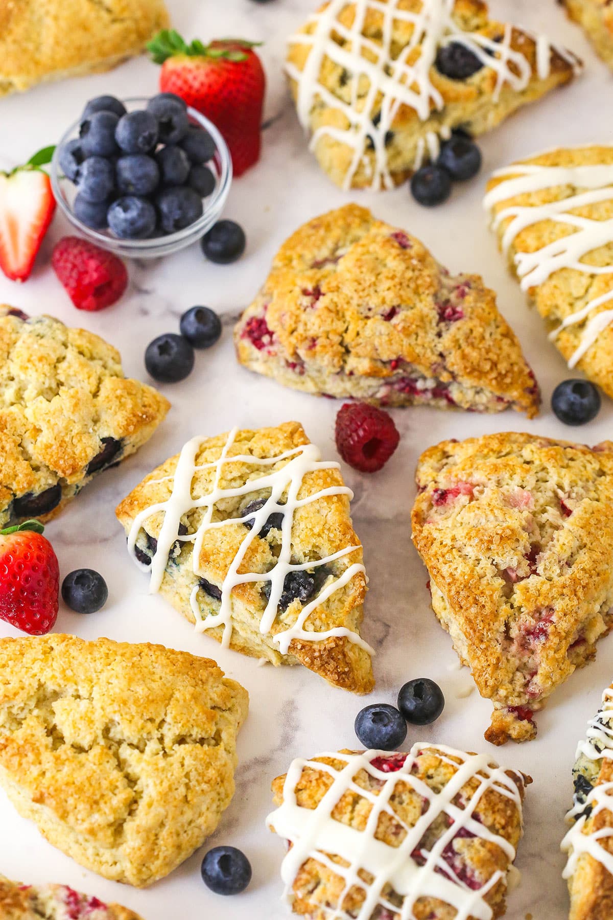A variety of scones spread across a work surface. Some plain, some iced, some with fruit, and everything in between!