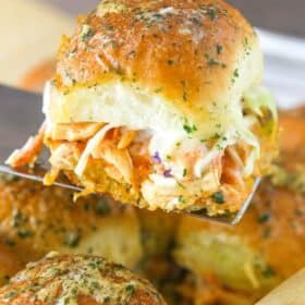 A spatula holding up a buffalo chicken slider.