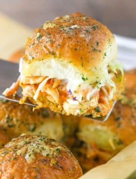 A spatula holding up a buffalo chicken slider.