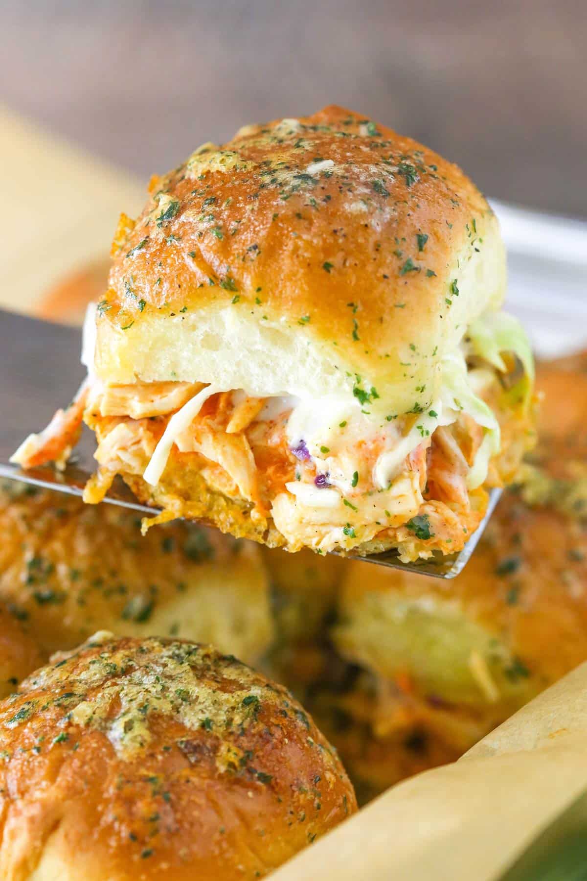 A spatula holding up a buffalo chicken slider.