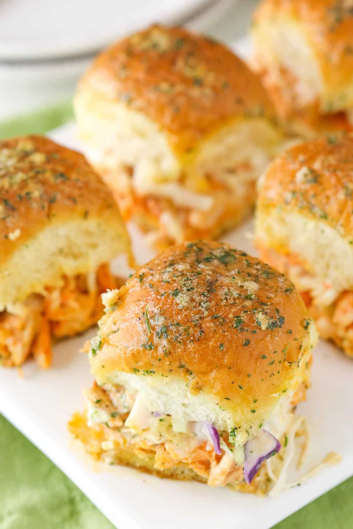 Buffalo chicken sliders on a white cutting board.