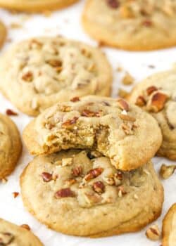 A pile of butter pecan cookies with a bite taken out of the top cookie.