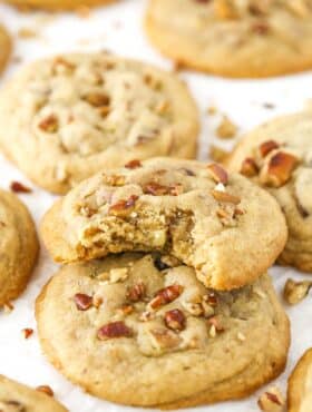 A pile of butter pecan cookies with a bite taken out of the top cookie.