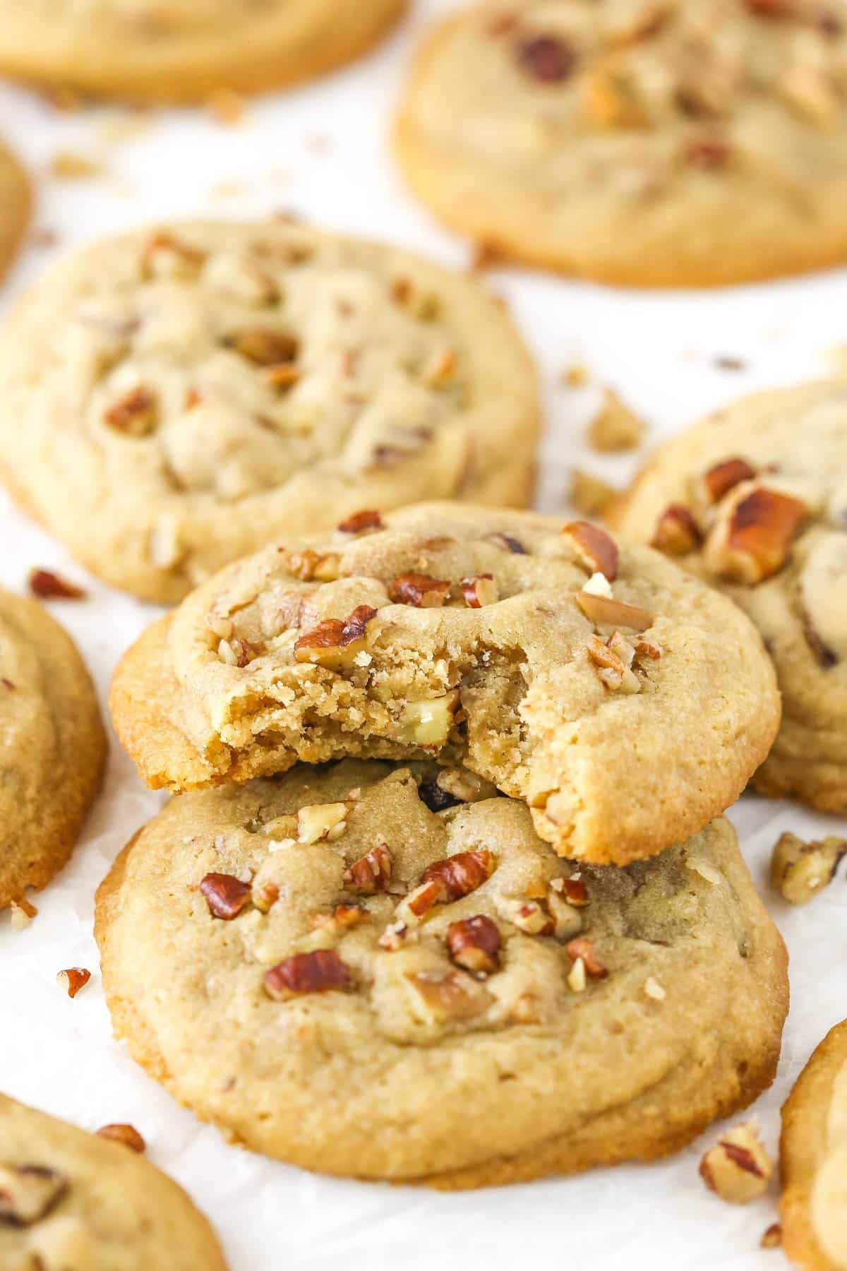 A pile of butter pecan cookies with a bite taken out of the top cookie.