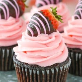 Close up of a chocolate covered strawberry cupcake on a silver tray.