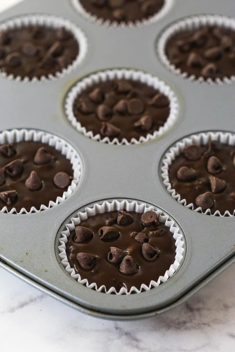 These Chocolate Muffins are so tender and supremely moist. Plus, they're loaded with chocolate flavor and packed with chocolate chips! Chocolate chocolate chip muffin batter in poured into muffin liners in a muffin pan.