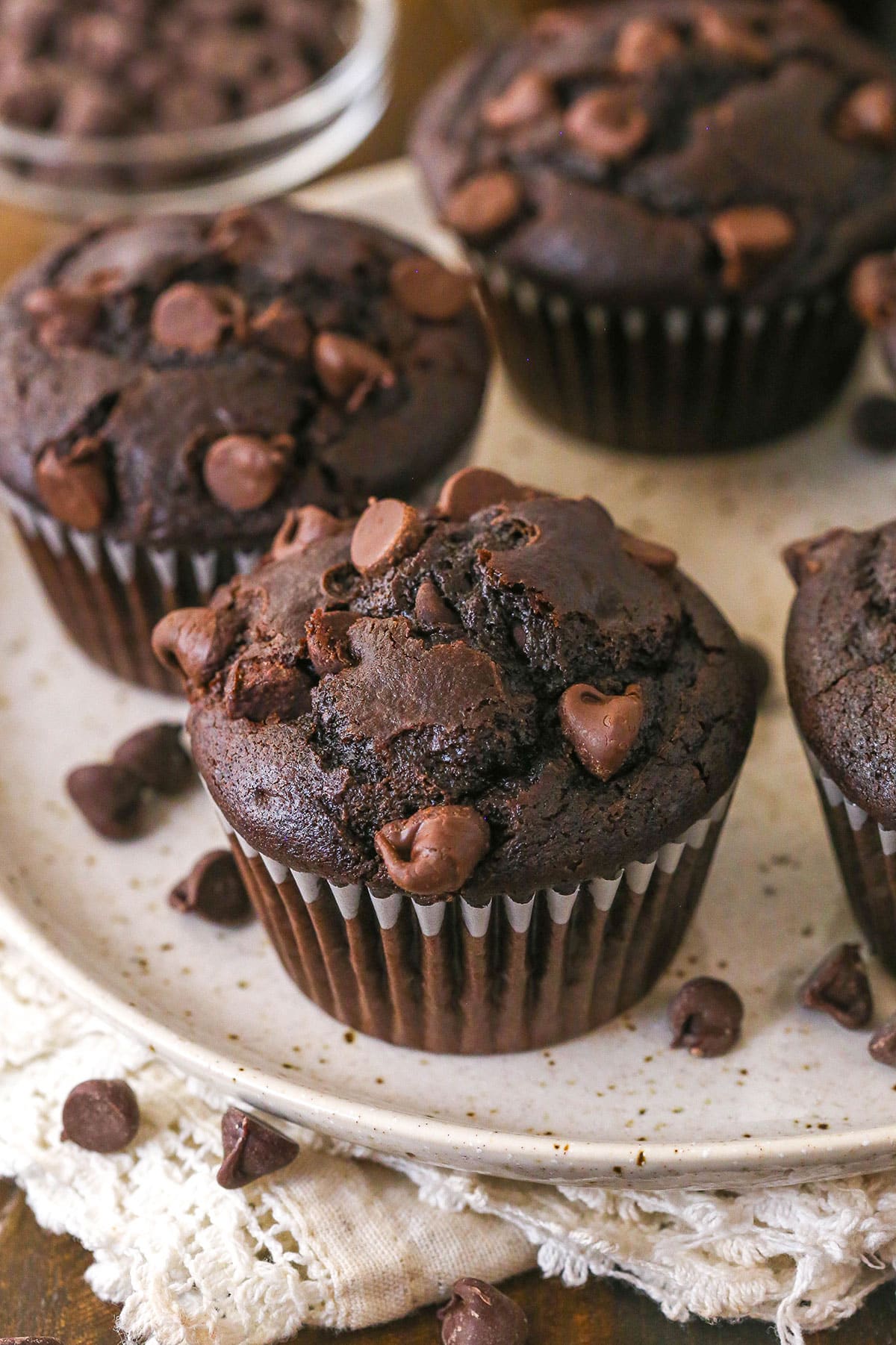These Chocolate Muffins are so tender and supremely moist. Plus, they're loaded with chocolate flavor and packed with chocolate chips! Closeup of chocolate muffins on a plate.