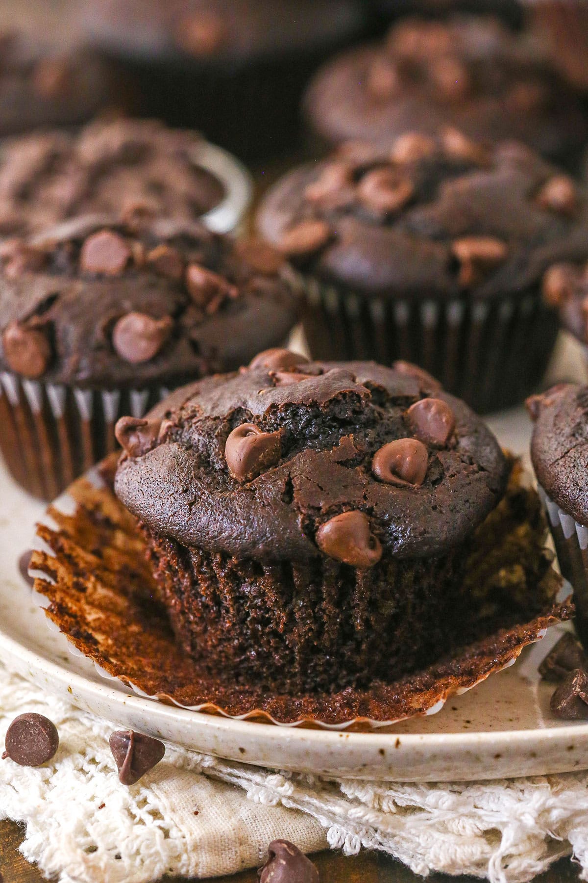 These Chocolate Muffins are so tender and supremely moist. Plus, they're loaded with chocolate flavor and packed with chocolate chips! A chocolate muffin with the liner peeled back.