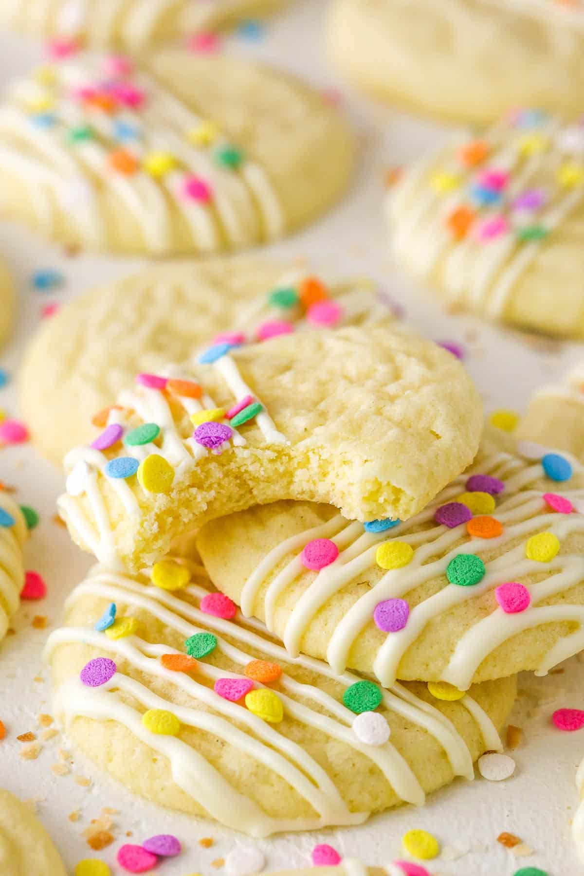 A pile of Coconut Sugar Cookies with a bite take out of the top cookie.