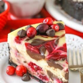 A slice of cranberry fudge swirl cheesecake on a small white dessert plate.