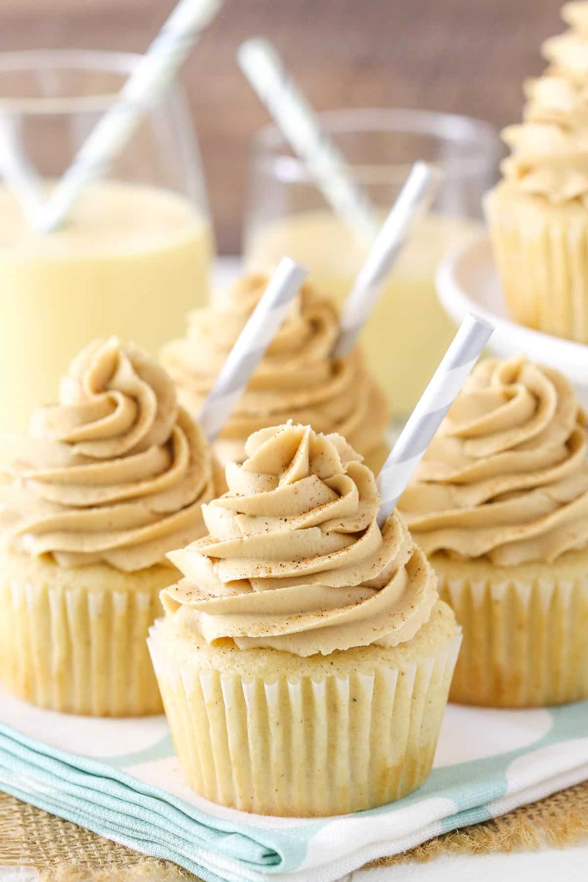Four eggnog latte cupcakes on a light blue napkin.
