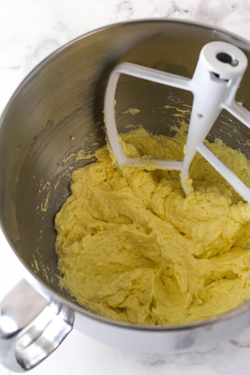 Beating egg yolks, lemon juice, lemon zest, and vanilla into creamed butter, oil, and sugar.