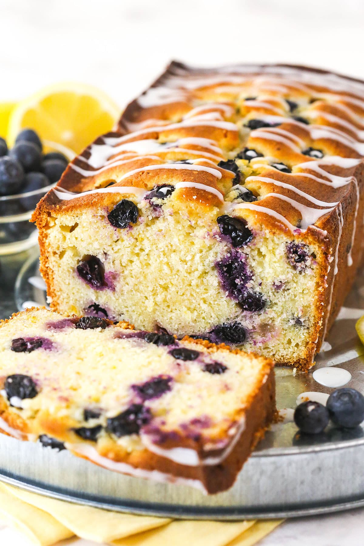 A loaf of lemon blueberry bread with a slice taken from it.
