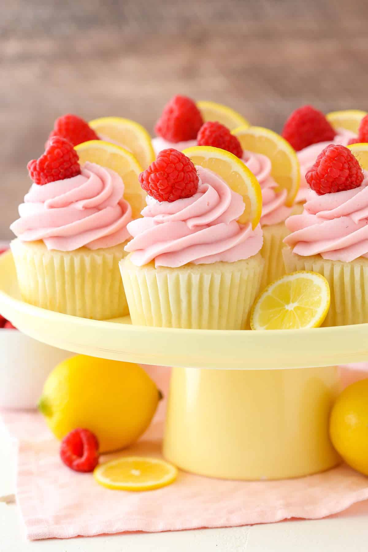 Lemon raspberry cupcakes on a yellow cake plate.