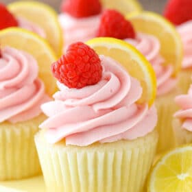 Close up of a lemon raspberry cupcake on a yellow cake plate.